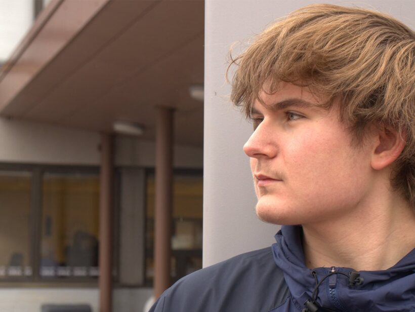 Henkilö katsoo tyhjyyteen ulko-ovien edessä.