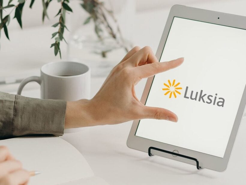 Tabletin näytöllä on Luksian logo. Sormet skaalaavat logoa suuremmaksi.