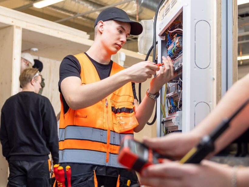 Opiskelija ruuvaa ruuvia sähkötauluun.
