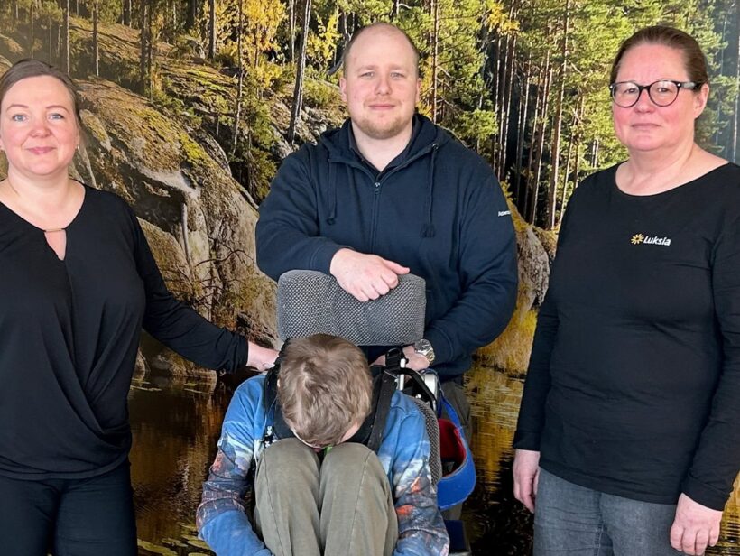 Neljä ihmistä ryhmäkuvassa, yksi ihminen istuu pyörätuolissa.