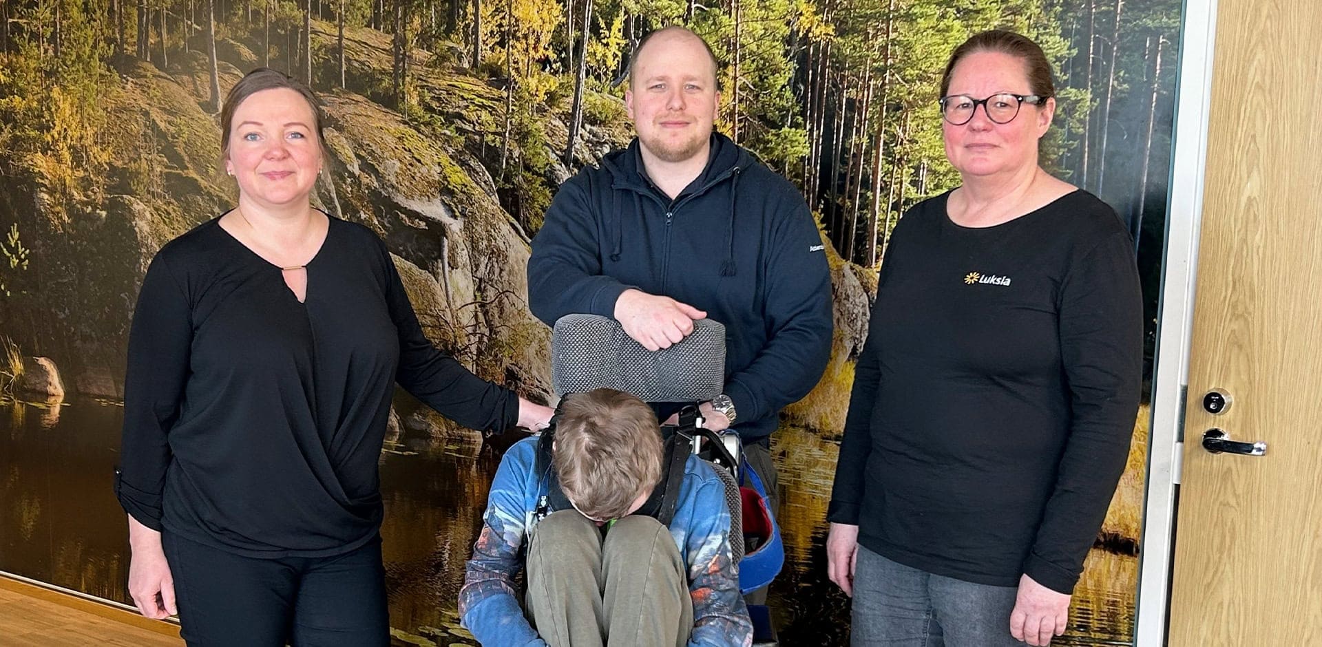 Neljä ihmistä ryhmäkuvassa, yksi ihminen istuu pyörätuolissa.