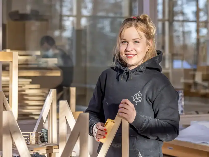Puutyöverstaalla henkilö mustassa hupparissa.