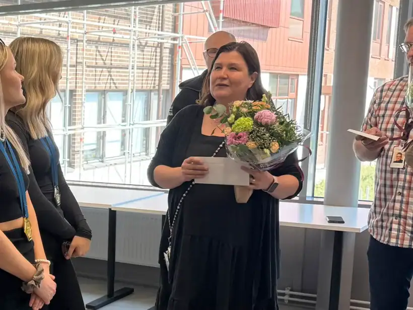 Kaksi ihmistä kukkakimput kädessä. Kaksi muuta henkilöä mitalit kaulassa.
