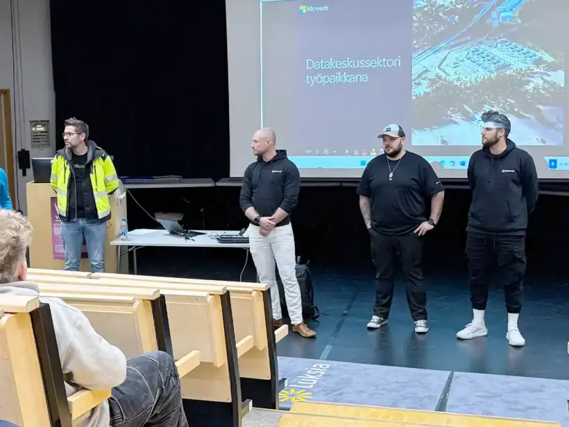 Luentosalin esiintymislavalla joukko ihmisiä.