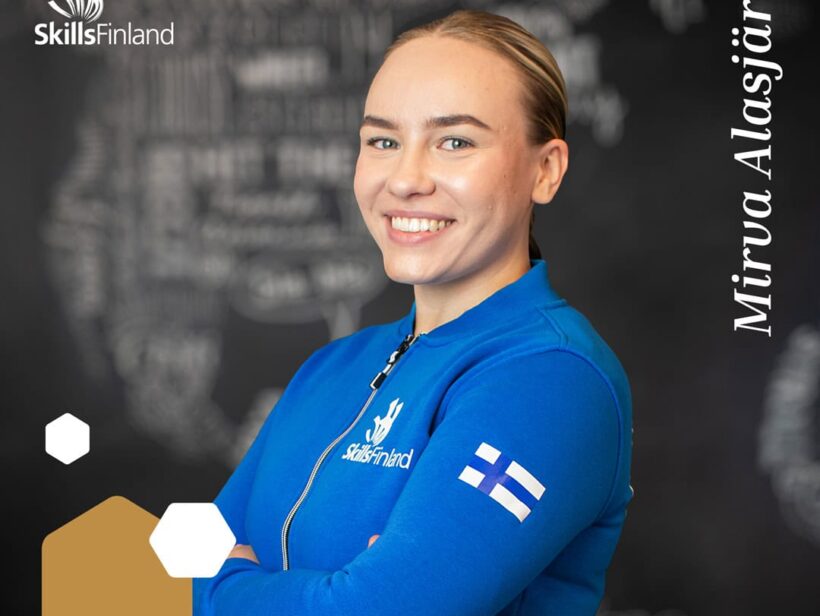 Henkilö hymyilee sininen edustusasu päällään.