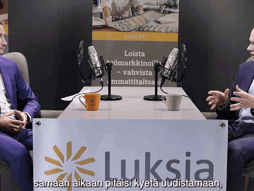 Kaksi henkilöä keskustelee pöydän ääressä.