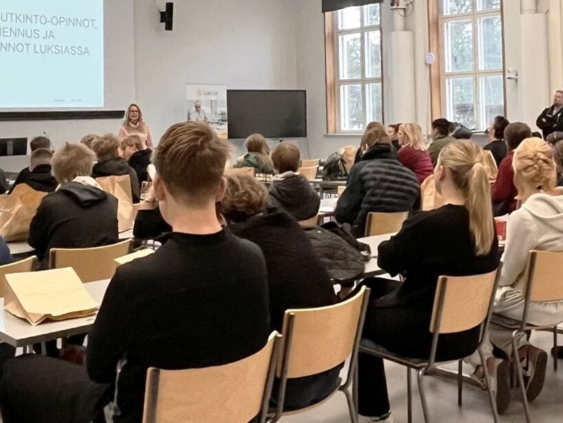 Ihmisiä luentosalissa, jossa luento käynnissä.