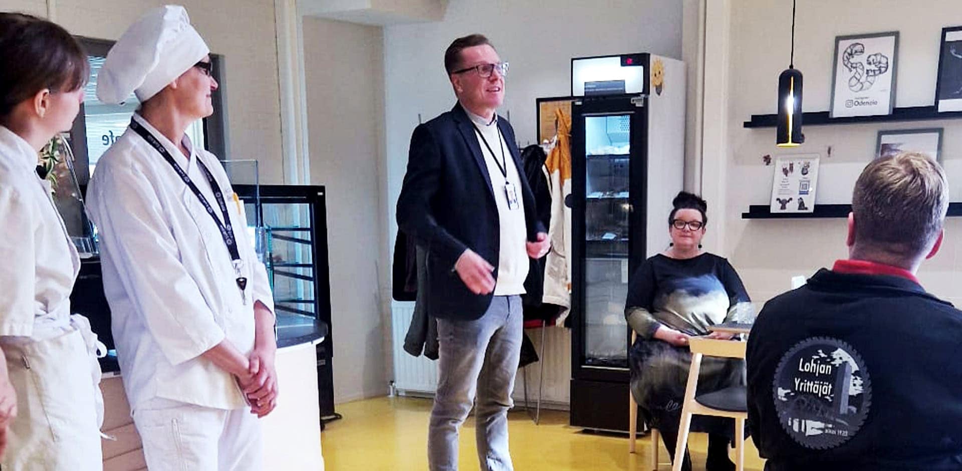Yleisnäkymä kahviosta, jossa asiakkaita ja henkilökuntaa.