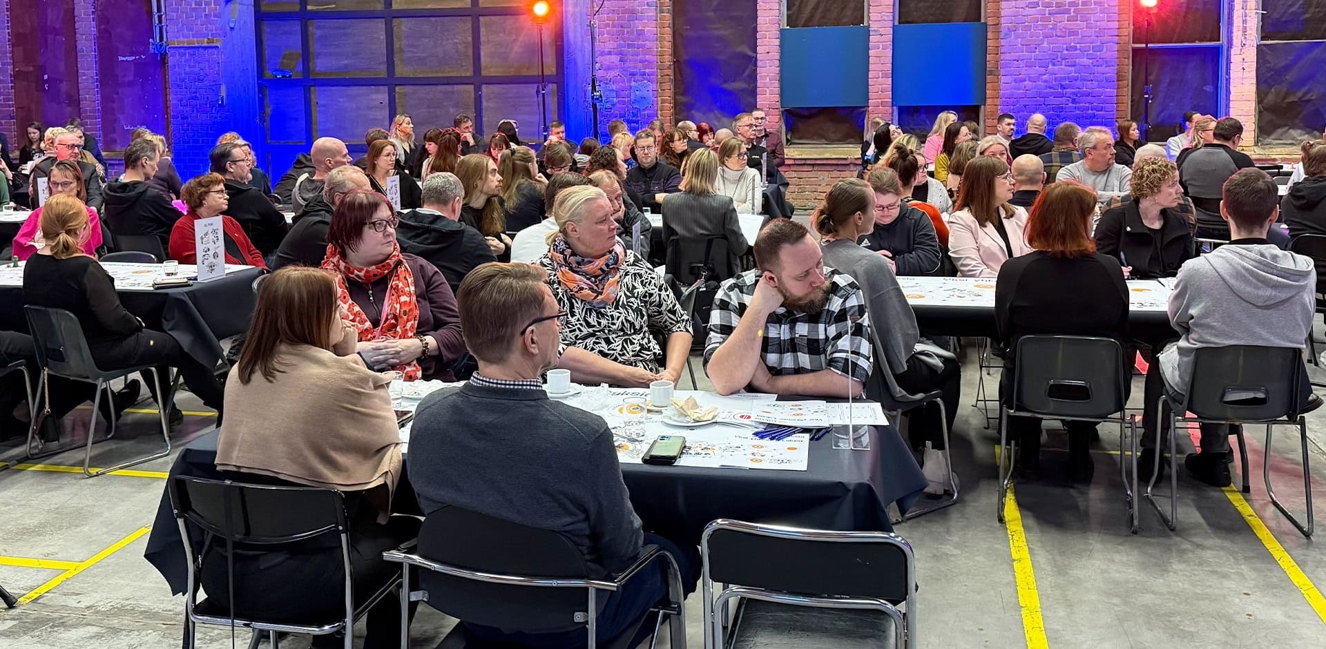 Ihmiset istuvat pöytien ääressä.