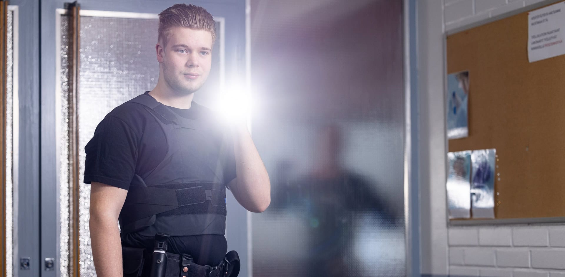 Turva-alan opiskelija seisoo taskulappu kädessä, joka on päällä.