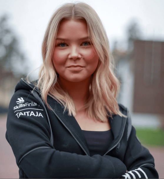 Vaaleahiuksinen henkilö mustassa hupparissa.