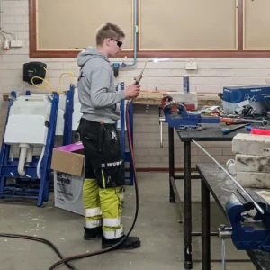 Hitsausta luokkahuoneessa. Yksi henkilö hitsaa.