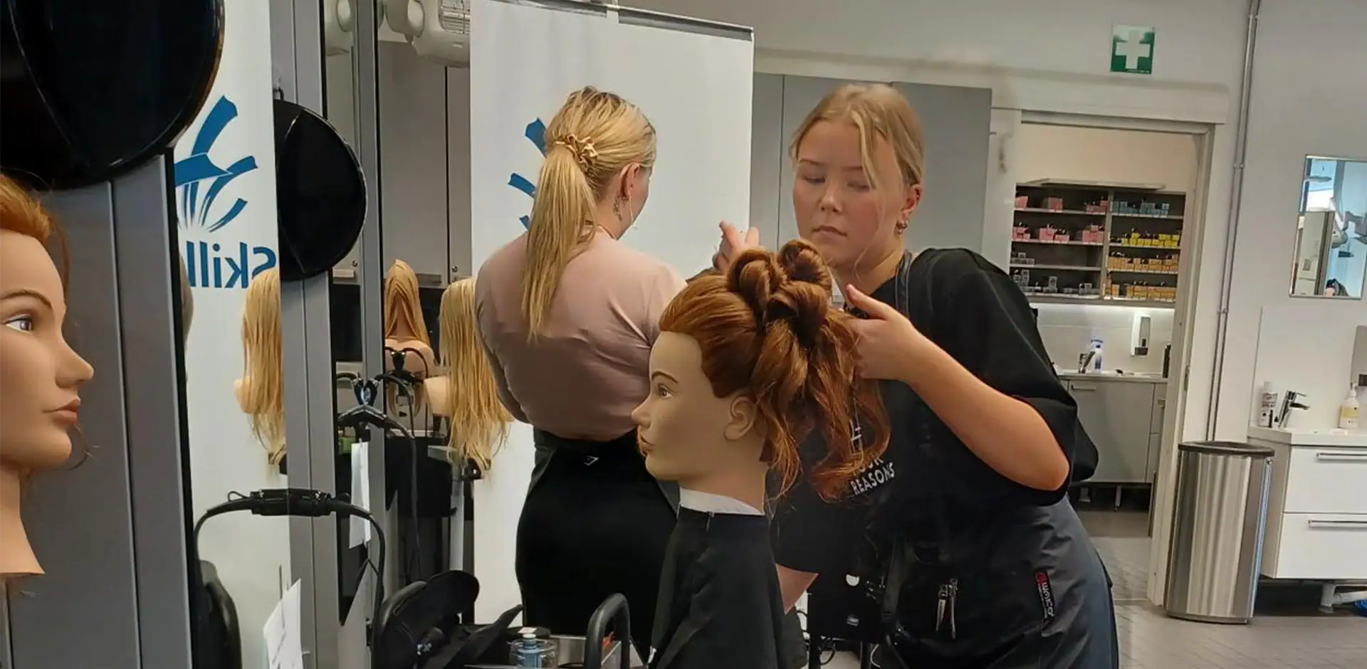 Henkilö tummassa asussa tekee kampausta kampauspäälle.