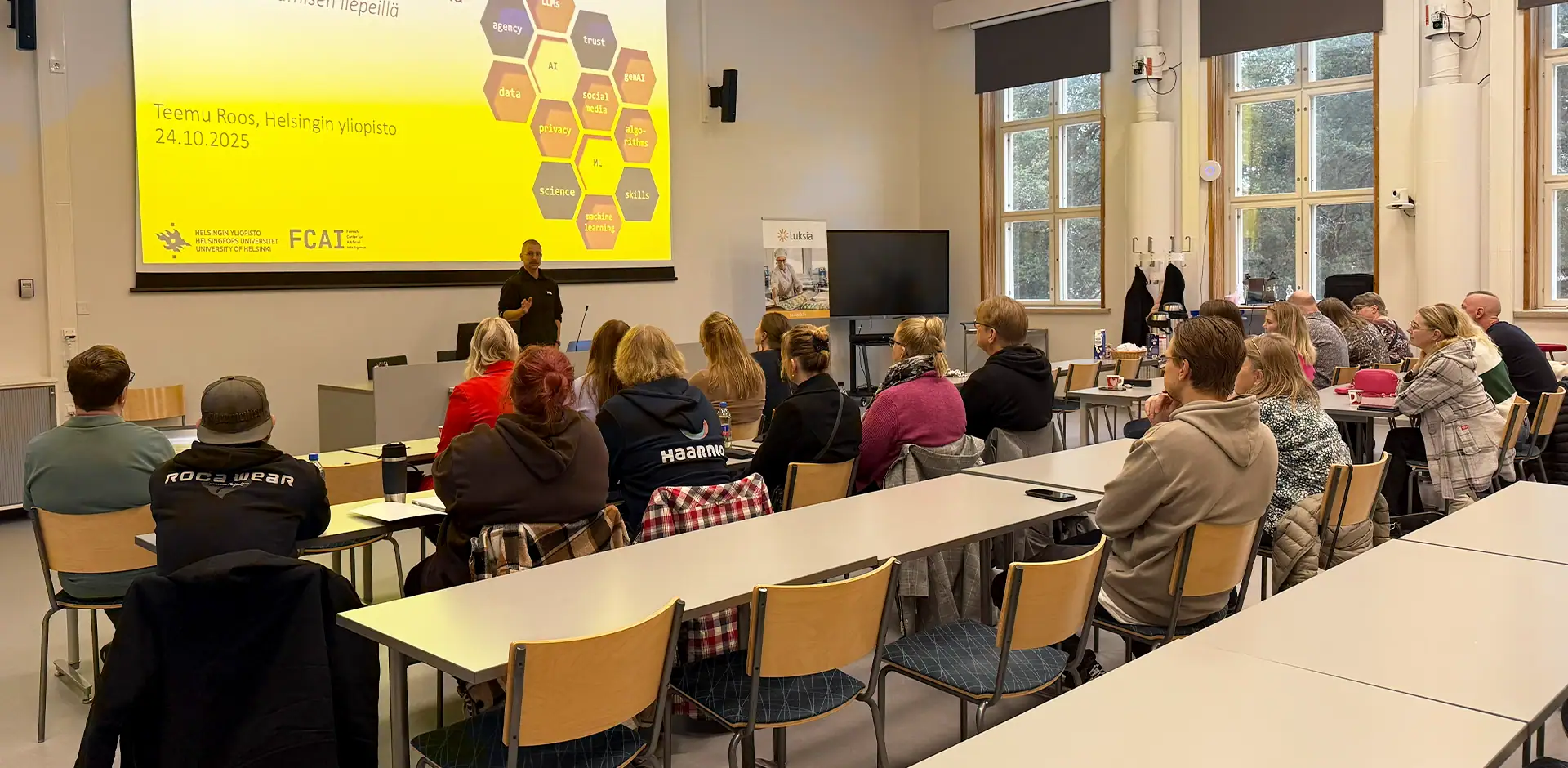 Ihmiset kuuntelevat esitystä luentosalissa.