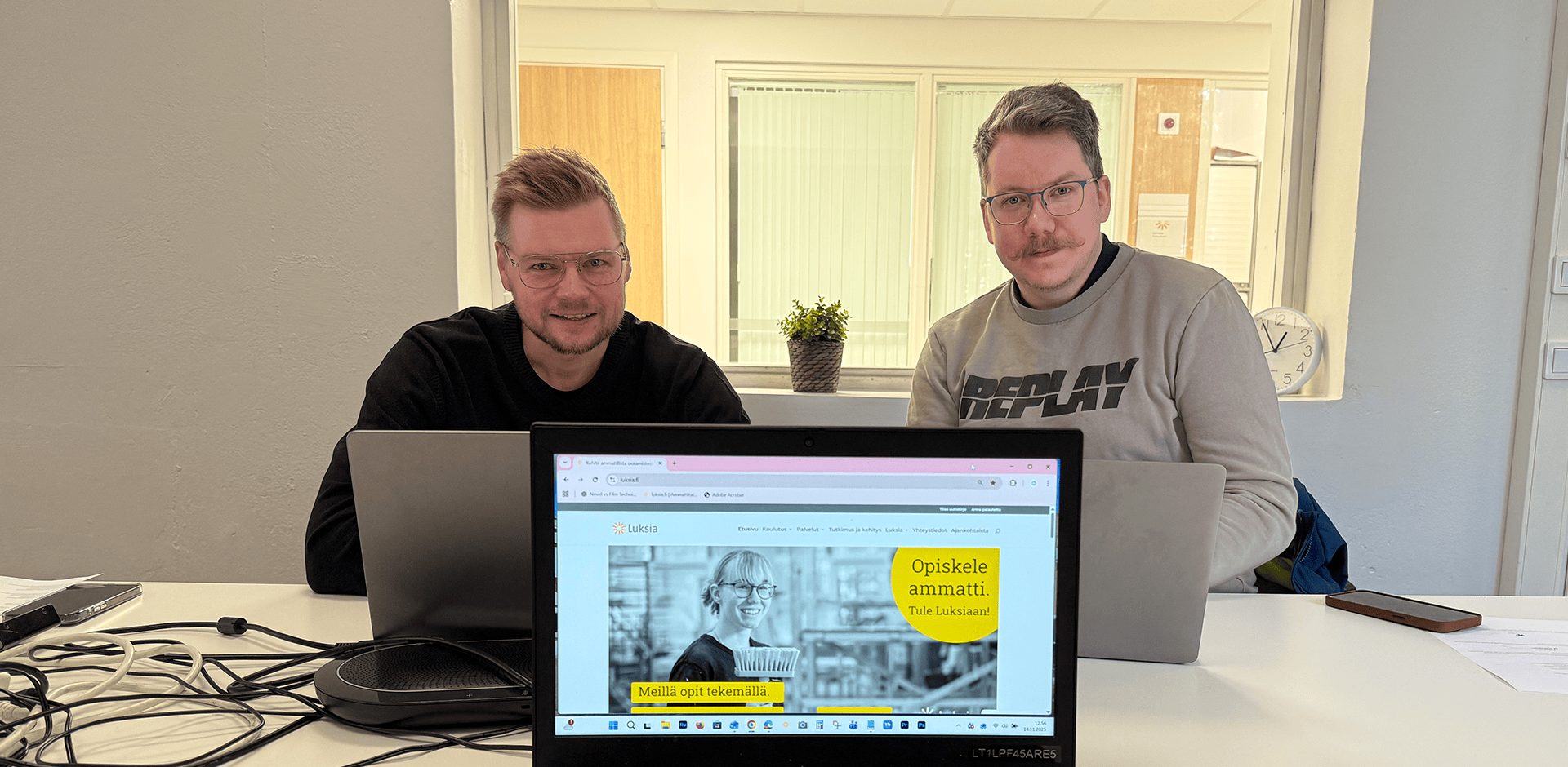 Kaksi henkilöä istuu neuvottelupöydän ääressä. Kuvassa myös tietokone, josta näkyy luksia.fi etusivu.