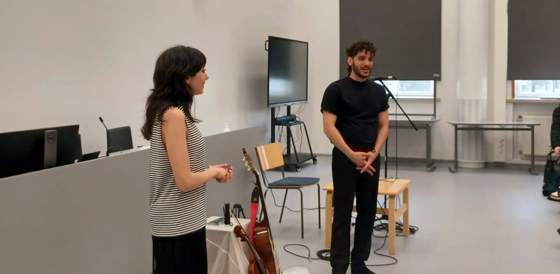 Kaksi henkilöä keskustelee luentosalissa yleisölle.